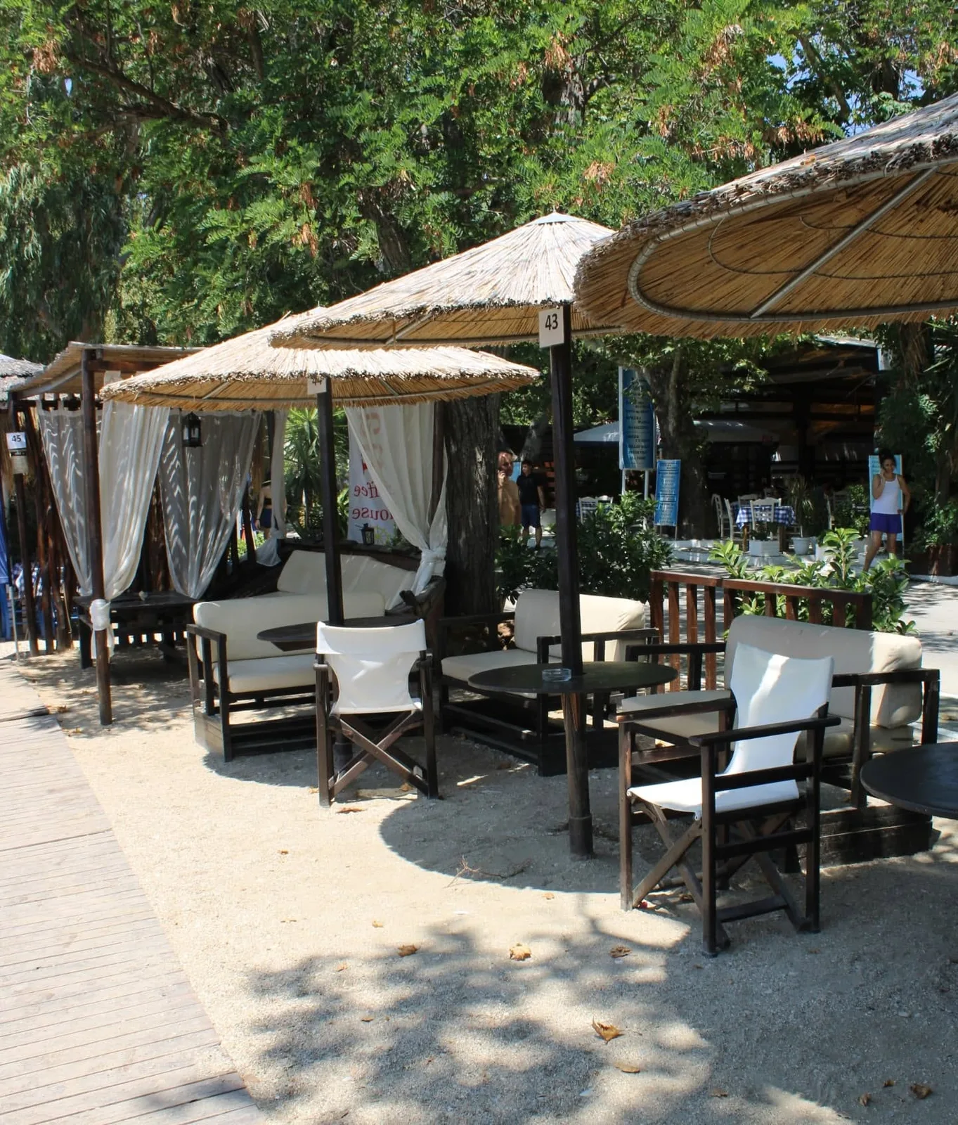 Lounge στην άμμο κάτω από ψάθινες ομπρέλες