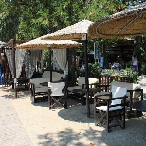 Lounge στην άμμο κάτω από ψάθινες ομπρέλες